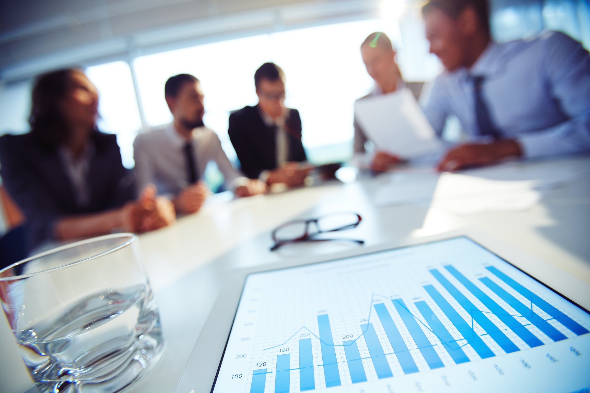 close-up-glass-water-tablet-with-executives-background close-up-glass-water-tablet-with-executives-background